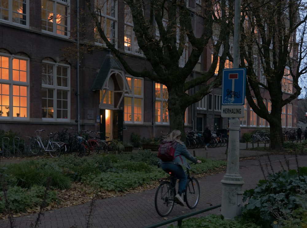 a woman riding a bike down a street next to a tall building