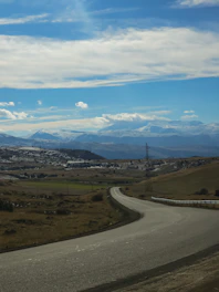 A winding road leading from an electric vehicle charging station to a bright solar panel field under a clear sky.