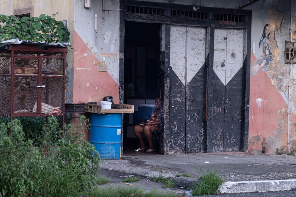uma mulher sentada em uma porta de um prédio degradado