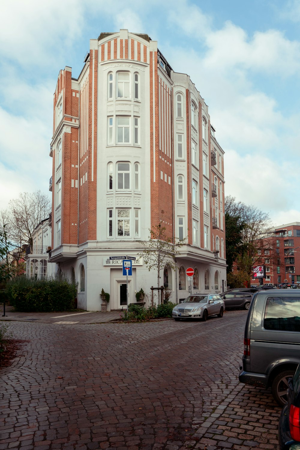 a large white and brown building with cars parked in front of it