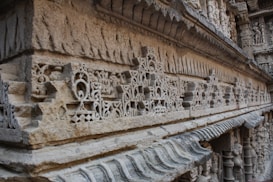 Intricate stone carvings cover the surface of an ancient architectural structure. The design includes ornate details and patterns that display exceptional craftsmanship typical of historical monuments.