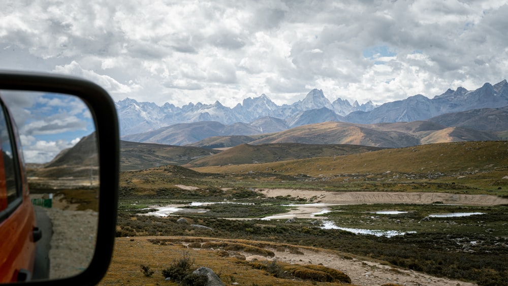 a car's side view mirror with mountains in the background