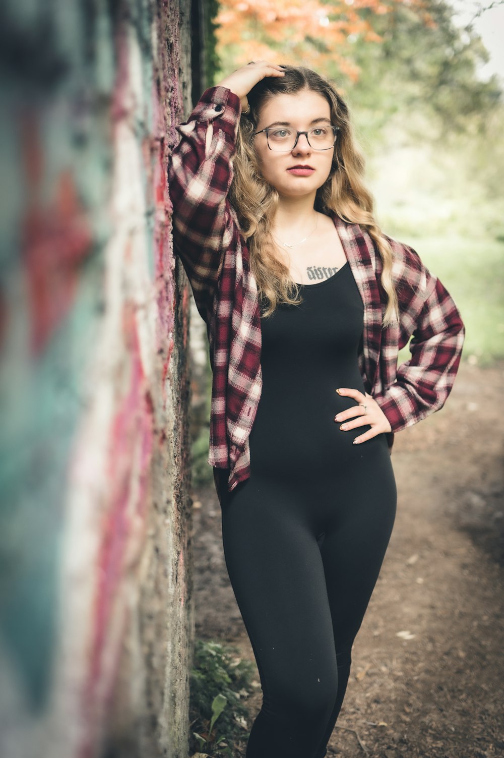 a woman wearing glasses leaning against a wall