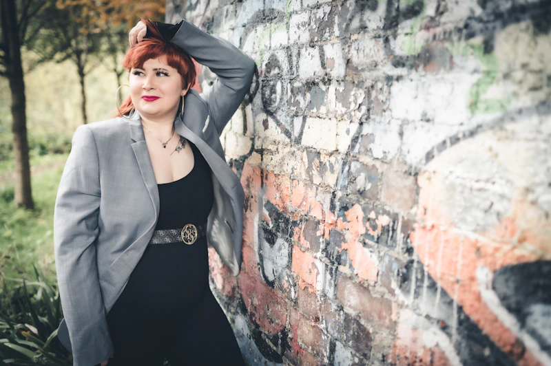 a woman leaning against a brick wall with her hand on her head