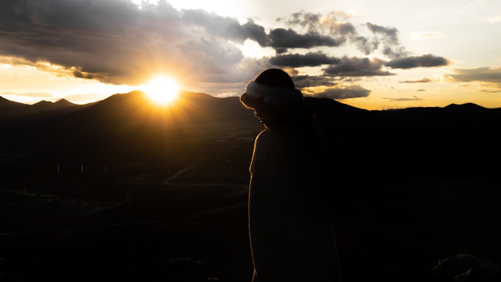 a person standing on top of a mountain at sunset