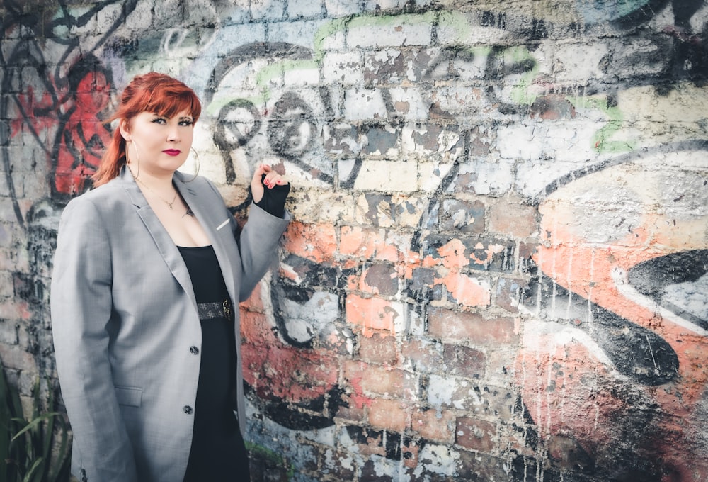 una mujer de pie frente a una pared cubierta de grafitis