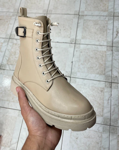 Close-up of handcrafted leather boots resting on rustic wooden floor.