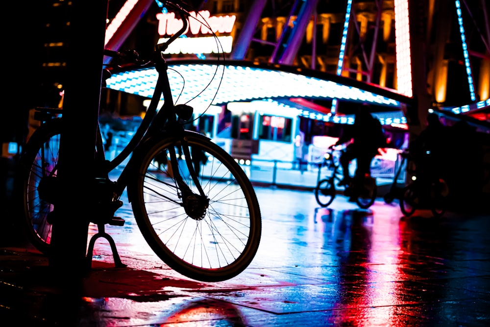 a bicycle parked next to a pole in front of a carousel