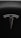 A sleek metallic emblem resembling a stylized letter 'T' is set against a textured black background, suggesting a modern and minimalist design aesthetic.