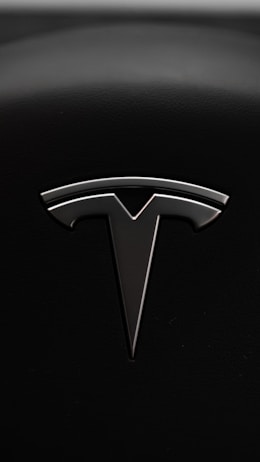 A sleek metallic emblem resembling a stylized letter 