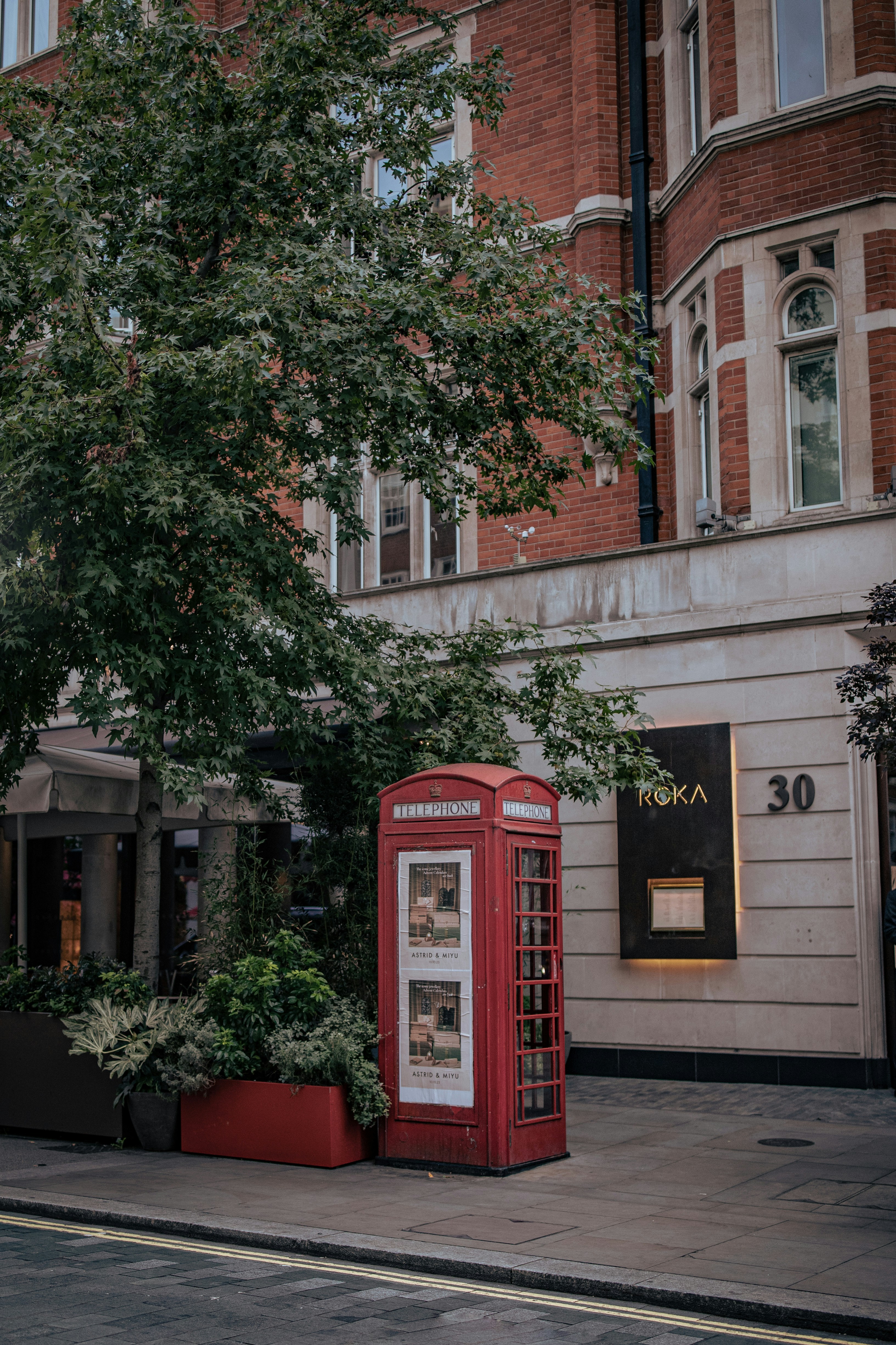 a red phone booth sitting on the side of a road