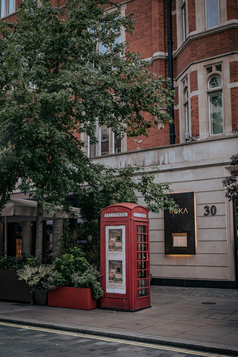 a red phone booth sitting on the side of a road