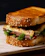 A happy customer enjoying a juicy grilled chorizo sandwich with fresh toppings.