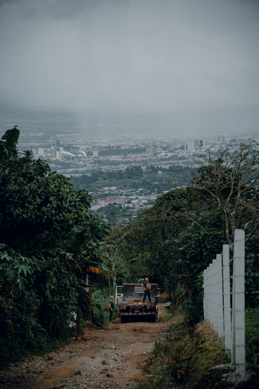 a man standing on the back of a truck on a dirt road