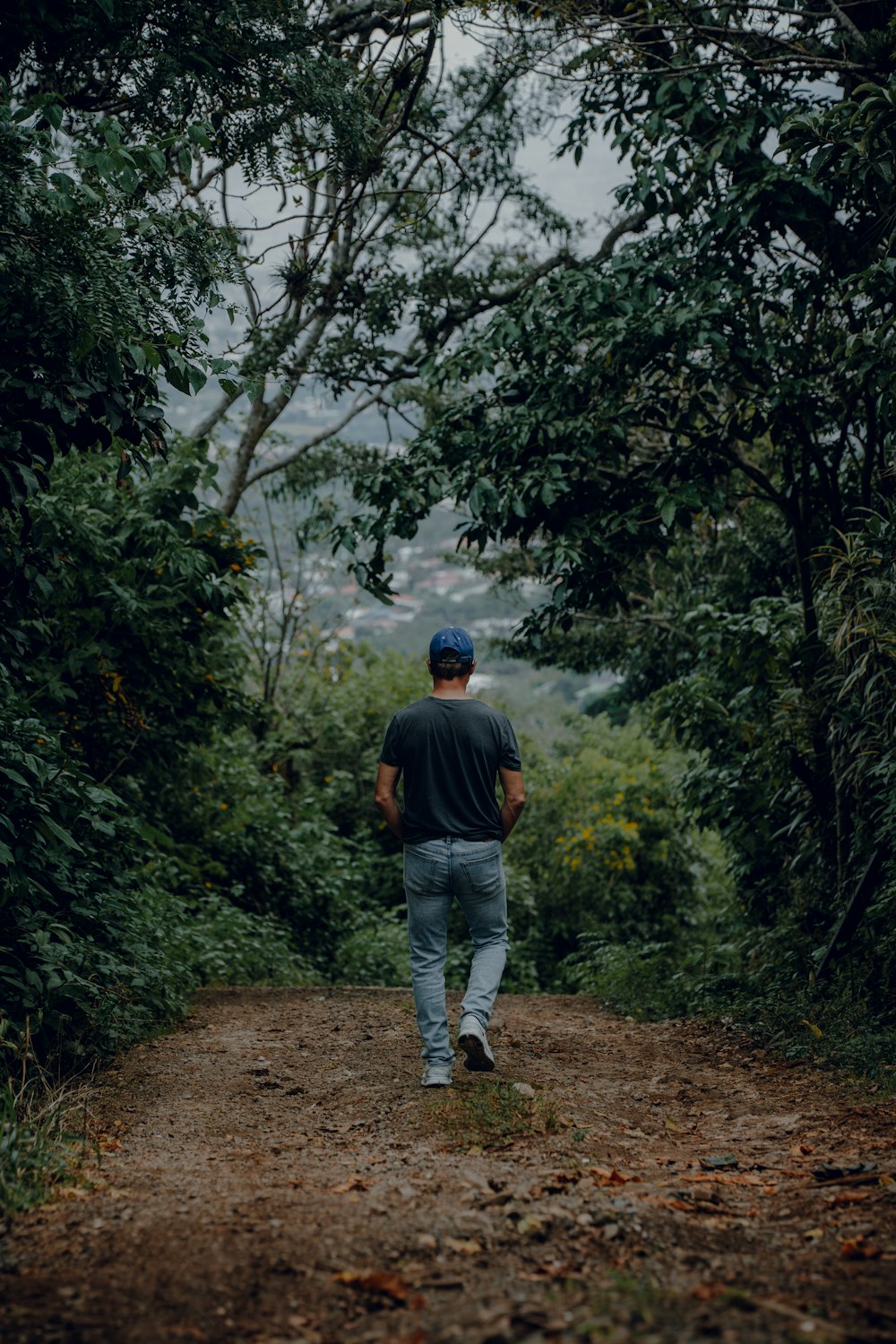 a man walking down a dirt road in the woods