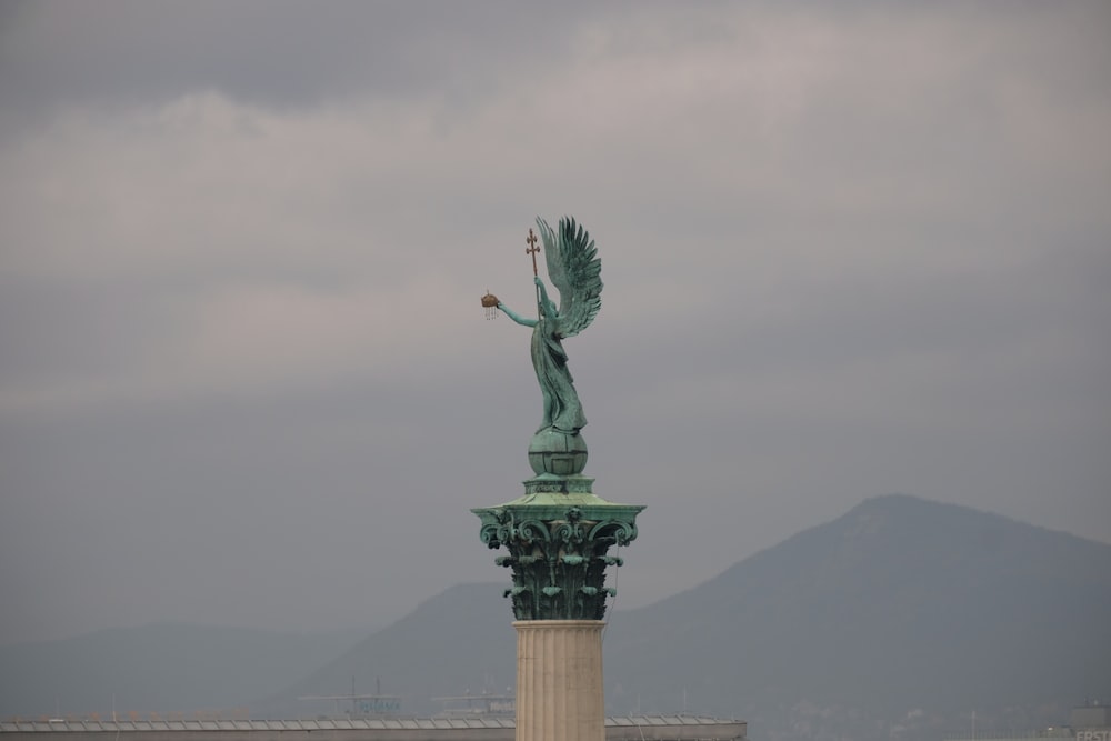 a statue of a woman holding a bird on top of a building