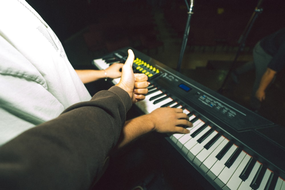 a person sitting at a keyboard giving a thumbs up