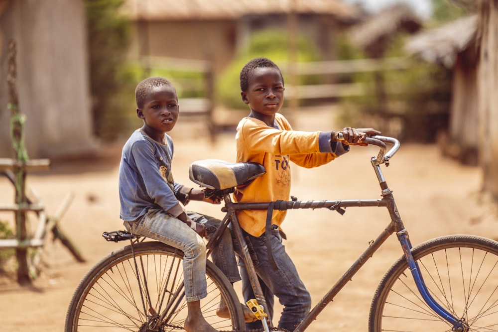two young boys sitting on top of a bike