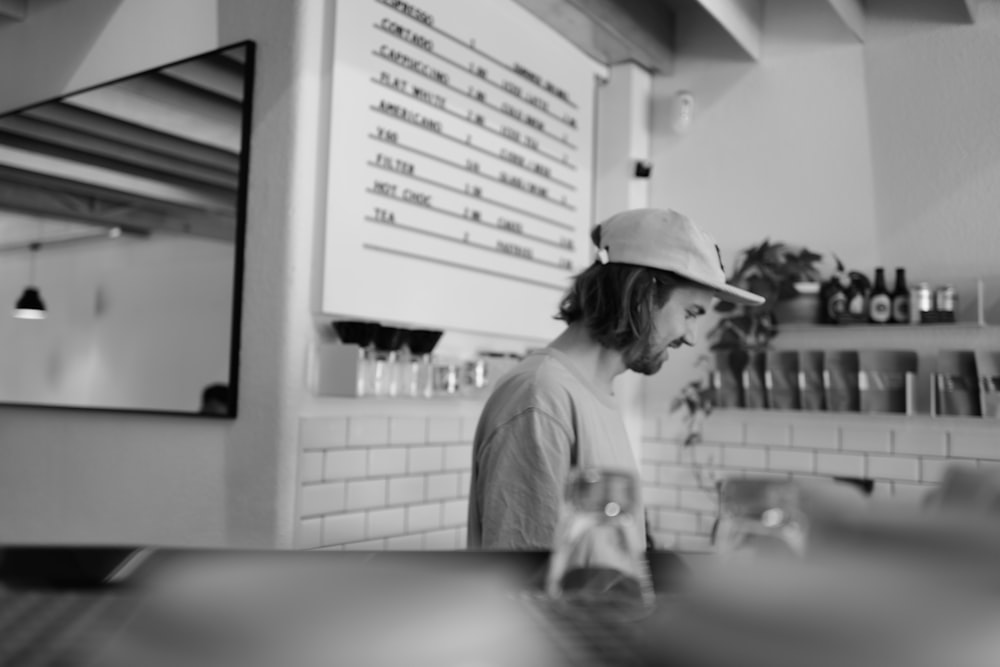 a man wearing a hat standing in front of a counter