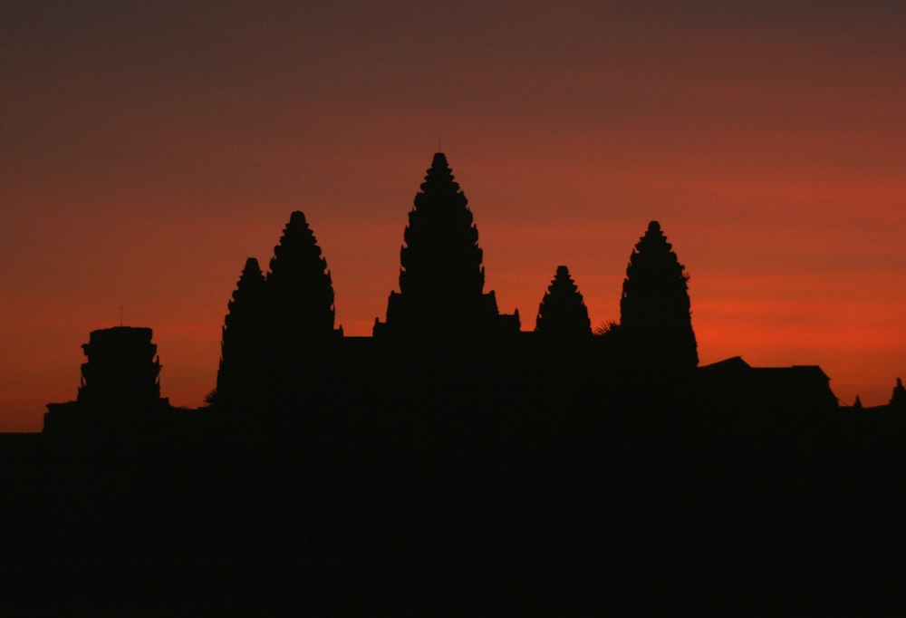 a silhouette of a building with a red sky in the background