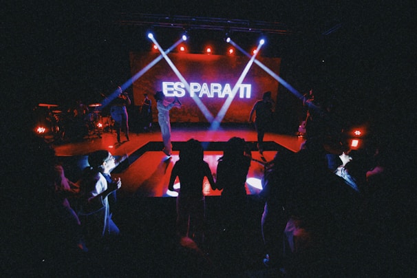 Pete Garza performing on stage with a black and cyan light backdrop.