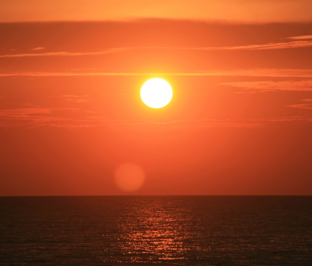 the sun is setting over the ocean on a cloudy day