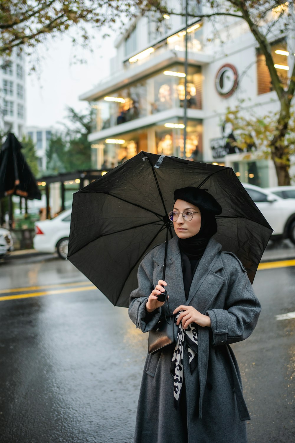 a woman standing on a street holding an umbrella