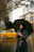 Man standing on a rainy street corner wearing a sleek Nimbusvale raincoat with an umbrella