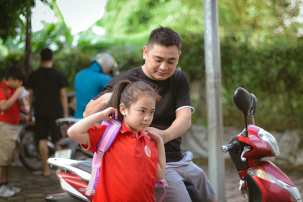 A driver partner helping a traveler with their luggage beside a parked scooter.