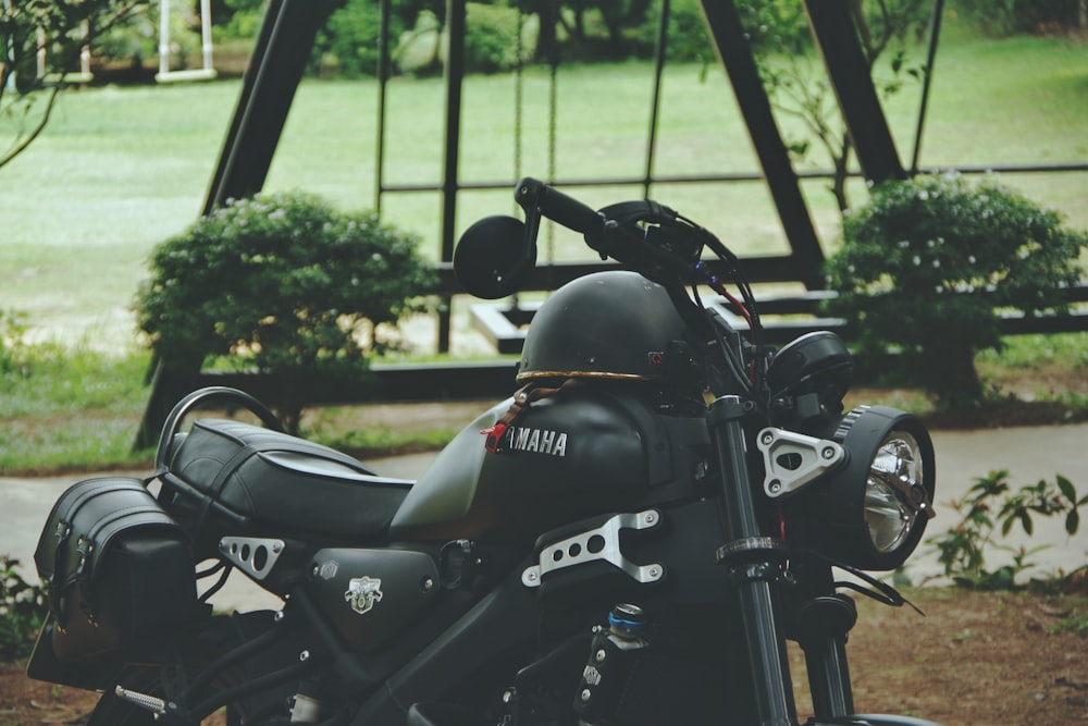 uma motocicleta preta estacionada em frente a um conjunto de balanço;