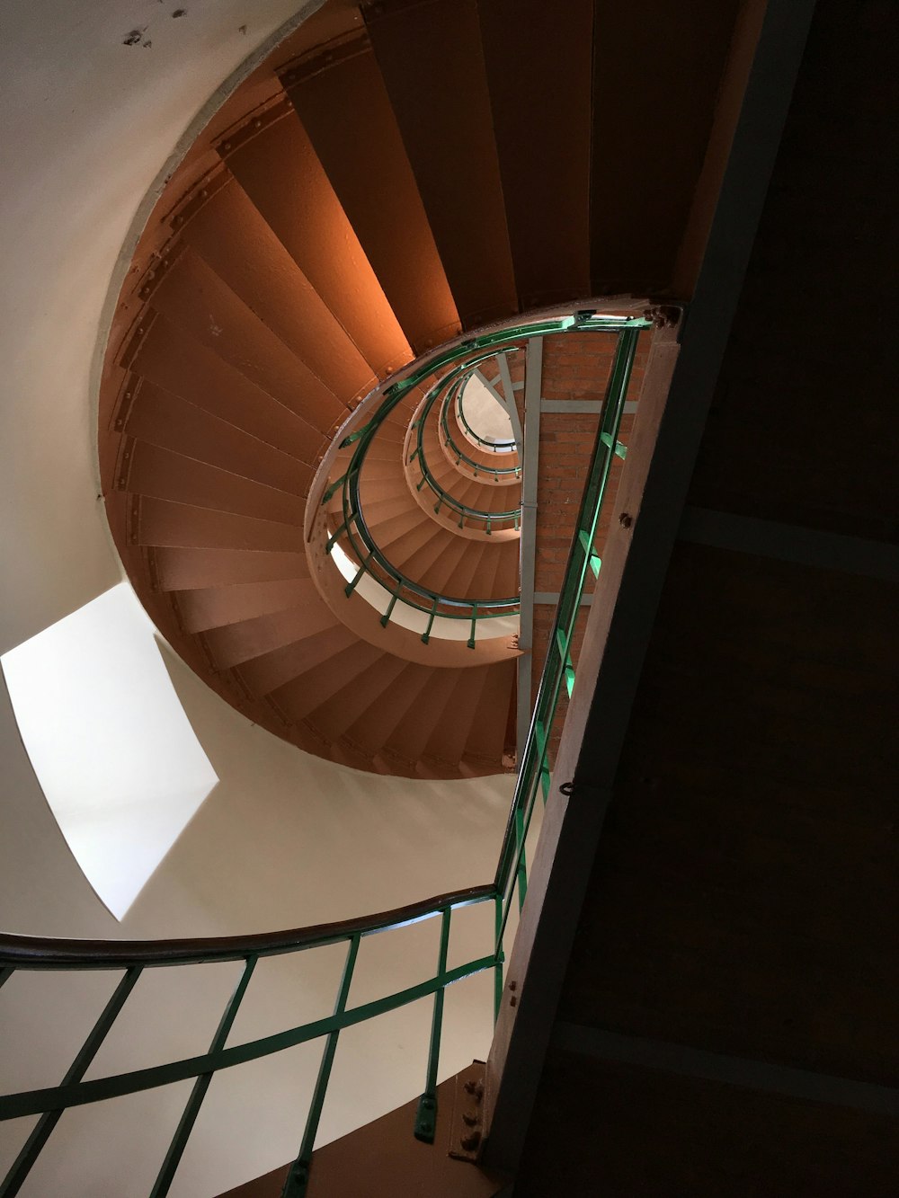 a spiral staircase in a building with green railings