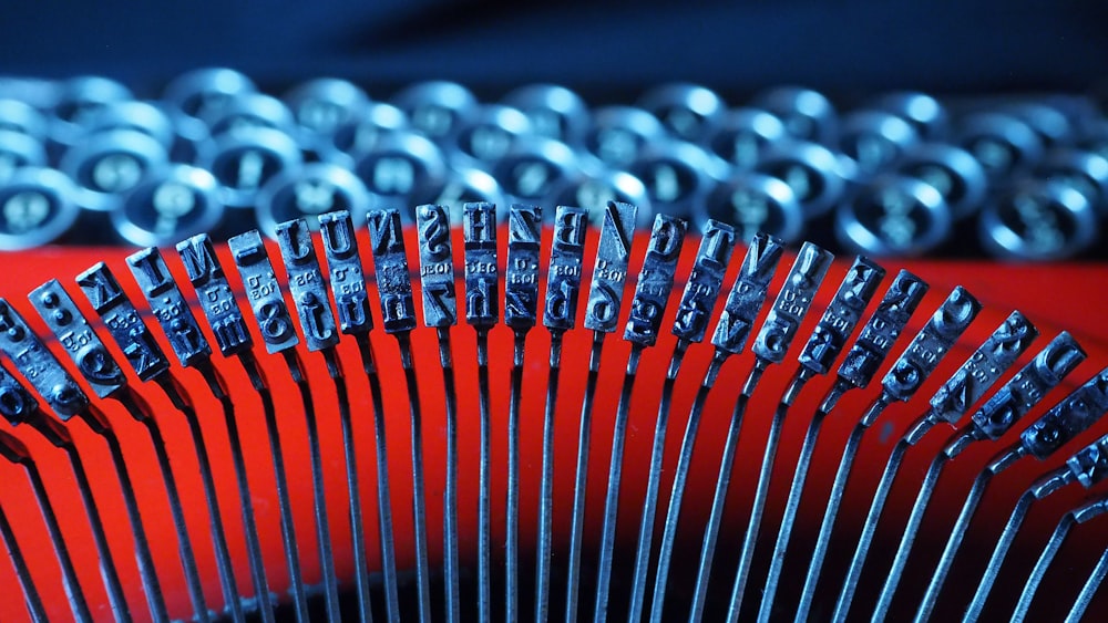 a close up of a metal typewriter on a red surface