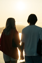 A couple enjoying a sunset on a serene beach, holding hands.