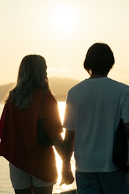 A happy couple enjoying a sunset cruise together, smiling and holding hands.
