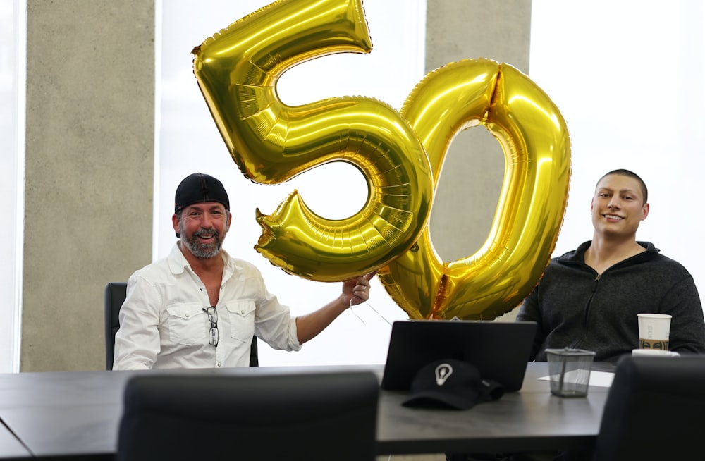 a man and a woman sitting at a table with a large balloon in the shape