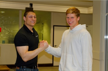 A manager shaking hands with a new tech team member in a bright workspace.
