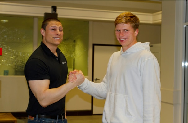 A friendly real estate agent shaking hands with a homeowner in front of a house.