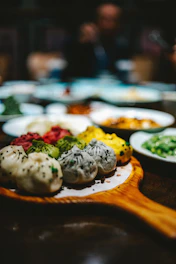 A colorful assortment of sushi rolls and dumplings arranged on a wooden board.
