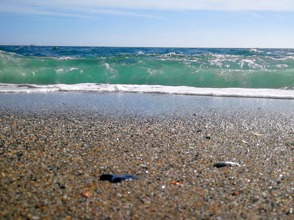 a close up of a beach with a wave coming in