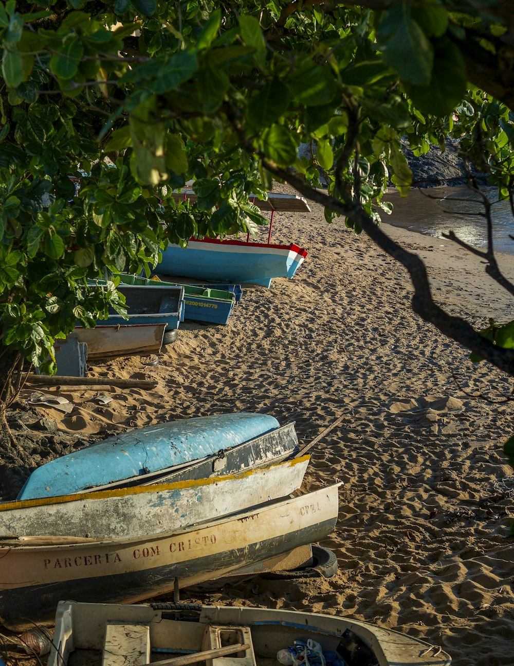 a row of boats sitting on top of a sandy beach