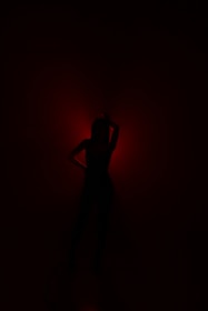 An artistic silhouette of a pornstar against a glowing red backdrop.