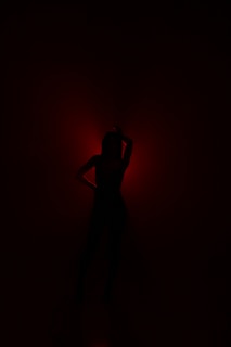 An artistic silhouette of a pornstar against a glowing red backdrop.