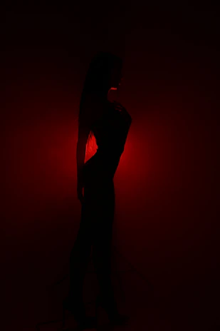 Elegant silhouette of a model against a dark backdrop with red light accents.