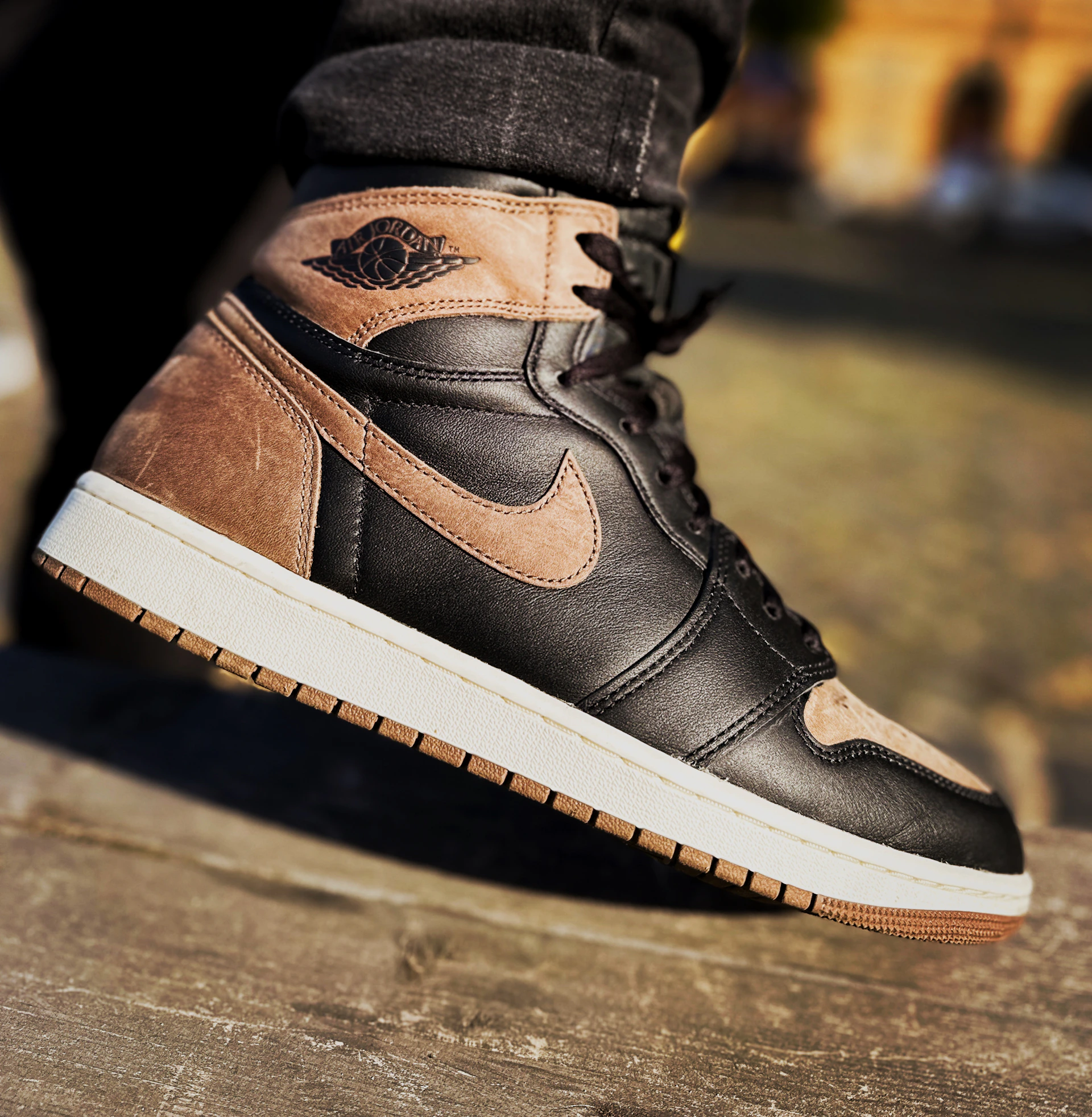 A close-up of a sleek leather sneaker with detailed stitching, resting on a rustic wooden floor.