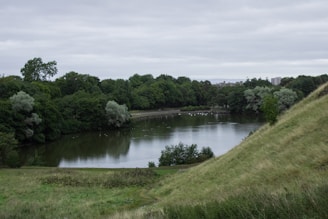A small lake surrounded by green fields and open land.