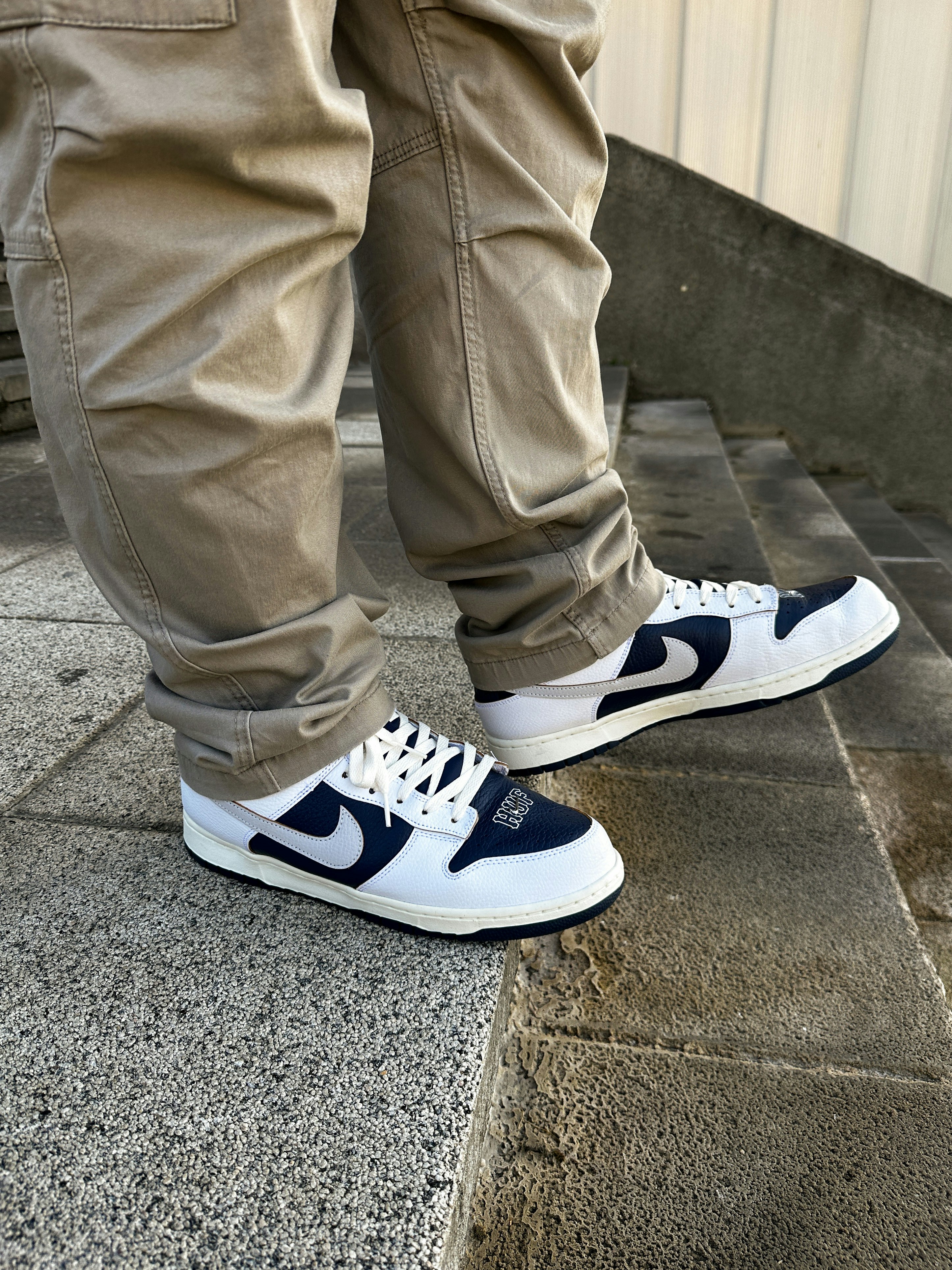 a person wearing white and blue shoes standing on a sidewalk