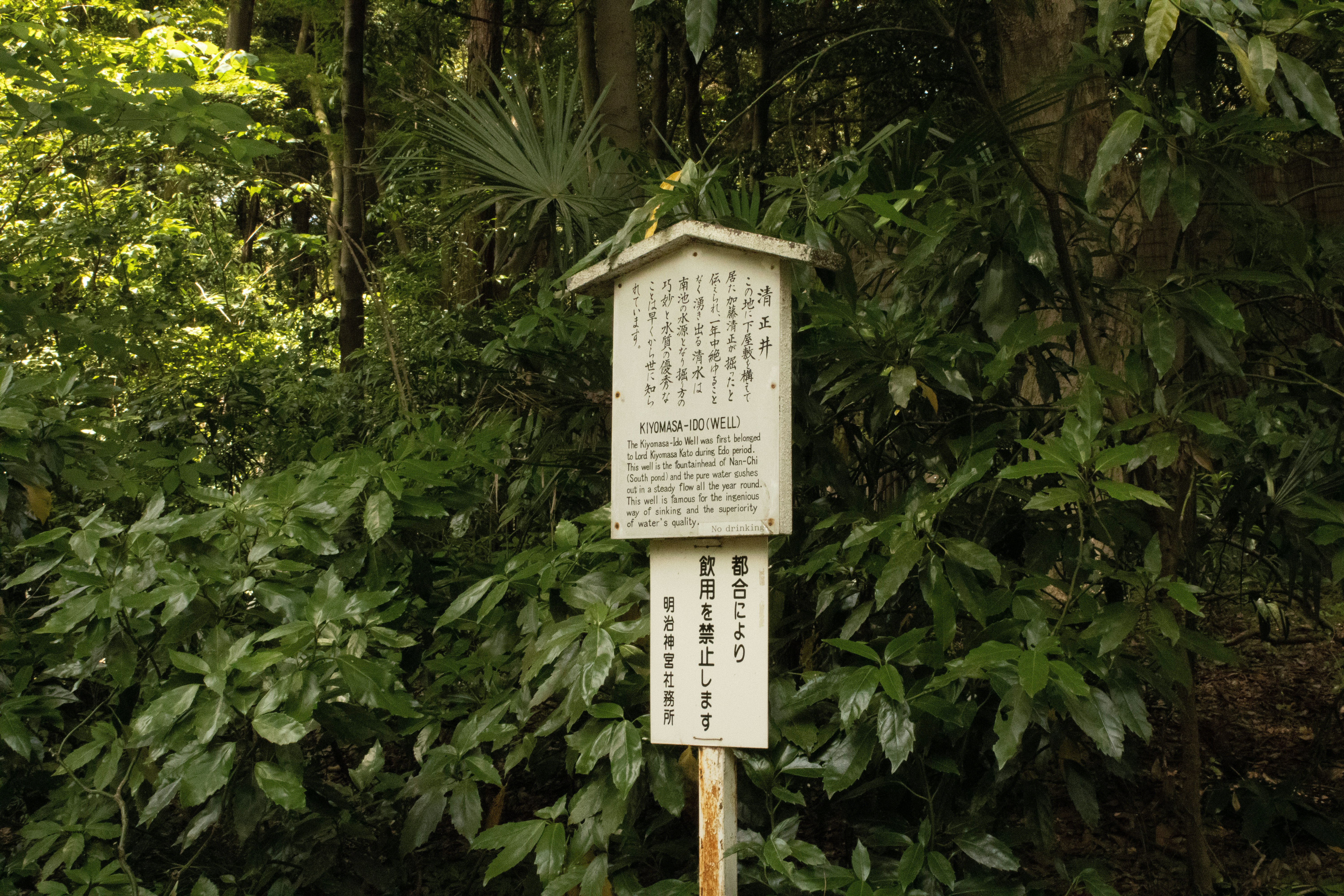 a sign in front of some trees and bushes