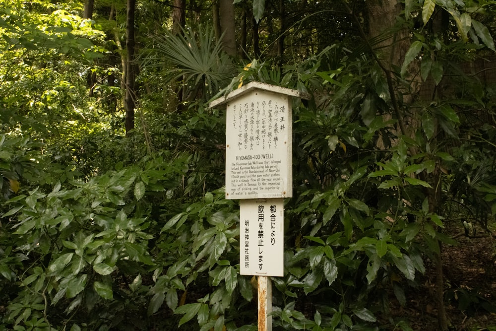 a sign in front of some trees and bushes