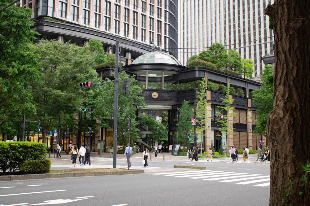 a group of people walking across a street next to tall buildings