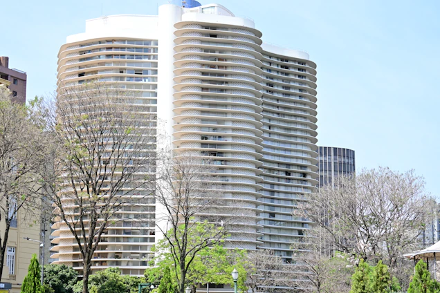 a tall white building sitting next to a lush green park